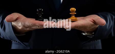 Stratégie et concept de planification des activités. Un homme d'affaires dans un costume sombre tient des pions d'échecs blancs et noirs. Stratégie et tactiques Banque D'Images