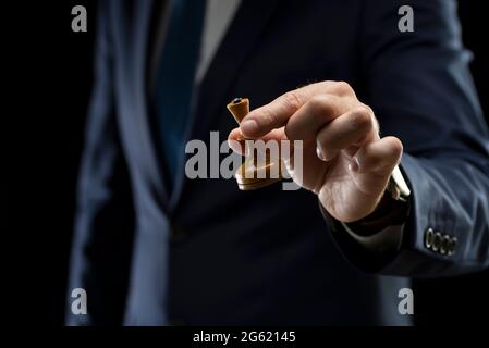 Stratégie et concept de planification des activités. Un homme d'affaires en costume sombre tient une reine d'échecs blanche entre ses mains. Stratégie et tactiques Banque D'Images