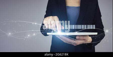 Concept de production logistique d'inventaire. Tablette blanche en main femme d'affaires avec hologramme numérique Code-barre étiquette de prix sur fond gris. Entrepôt et Banque D'Images