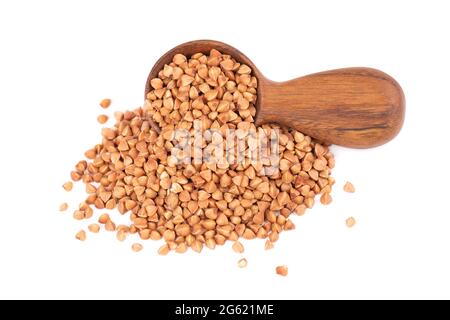 Grains de sarrasin rôtis dans une cuillère en bois, isolés sur fond blanc. Gruaux de sarrasin brun sec. Banque D'Images