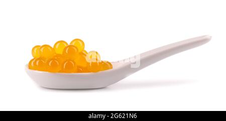 Perles de tapioca jaune pour le thé à bulles isolées sur fond blanc. Perles de tapioca dans une cuillère en céramique. Banque D'Images