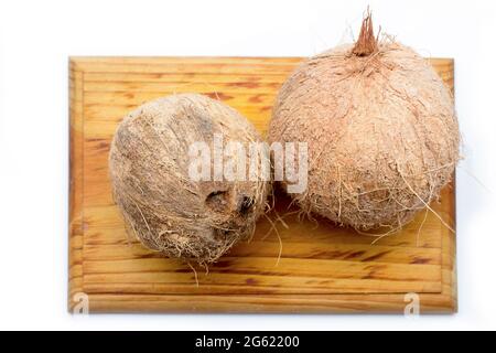 Noix de coco entières sur un panneau en bois sur fond blanc. Fruits tropicaux des côtes des Caraïbes Banque D'Images