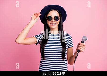 Photo portrait d'une femme souriante tenant un casque microphone dans les mains isolées sur fond rose pastel Banque D'Images