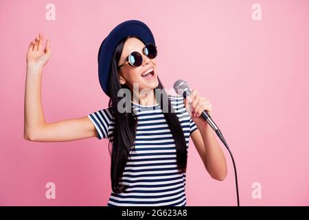 Photo portrait de femme insouciante chantant tenant le microphone dans une main isolée sur fond rose pastel Banque D'Images