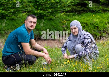 Un jeune couple musulman se squat sur l'herbe et regarde la caméra Banque D'Images