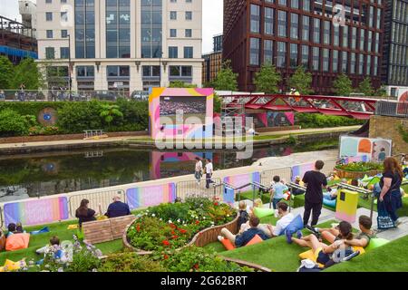 Londres, Royaume-Uni. 1er juillet 2021. On voit les gens regarder le championnat de tennis de Wimbledon sur un écran en plein air à Granary Square à King's Cross, Londres.Summer Love, un festival de cinéma en plein air gratuit des cinémas Everyman, présentera des films, ainsi que Wimbledon et Tour de France, Sur un grand écran extérieur tout au long de la journée et en soirée du 1er au 25 juillet 2021. Crédit : SOPA Images Limited/Alamy Live News Banque D'Images