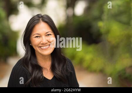 Portrait d'une femme asiatique assise à l'extérieur. Banque D'Images