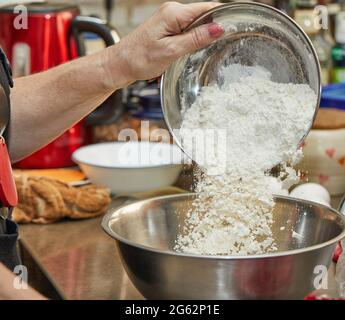 Le chef verse de la farine dans un bol pour préparer une tarte aux cerises, une clafoutis. Recette étape par étape Banque D'Images