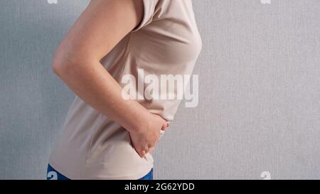 Femme méconnaissable tenant le ventre avec une douleur sévère, vue latérale. Banque D'Images