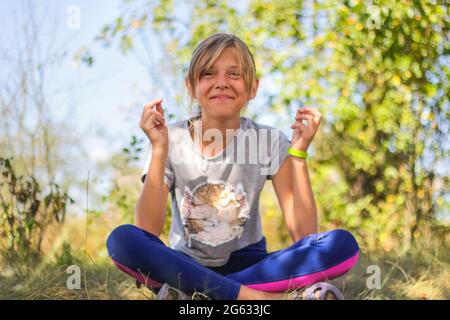 Défocus préadolescence caucasienne pratiquant le yoga dans le parc, la forêt, à l'extérieur, à l'extérieur. Méditation, concentration, mantra. Style de vie bien-être. Portrait de s Banque D'Images