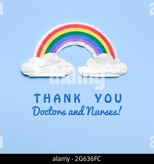 Arc-en-ciel avec nuages. Texte Merci médecins et infirmières. Merci à NHS pour lutter contre les pandémies. Motivation carré plat sur fond bleu clair. Banque D'Images