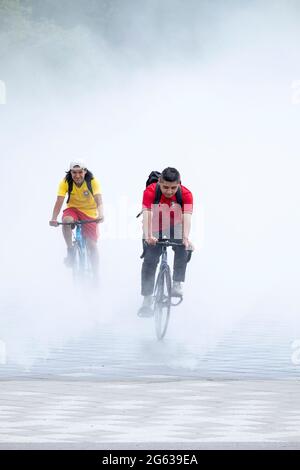 Les motards émergent de la fontaine des Foires, un jardin de brume qui reproduit un des expositions du monde 64. À Flushing Meadows Park, Queens, New York. Banque D'Images