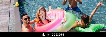 joyeux amis multiethniques se détendant dans la piscine ensemble, bannière Banque D'Images