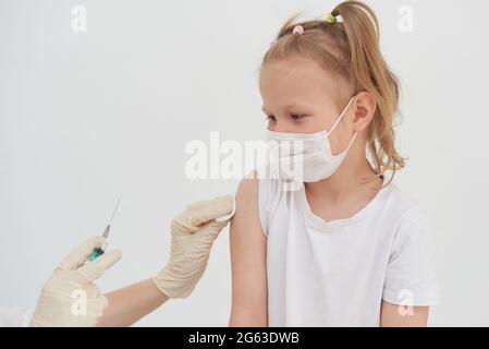 Une petite fille a peur des vaccinations, des injections et des vaccinations. L'enfant est vacciné contre le coronavirus. Banque D'Images