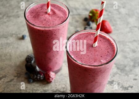 Deux smoothies aux baies mélangées dans de grands verres décoratifs sur la surface en pierre Banque D'Images