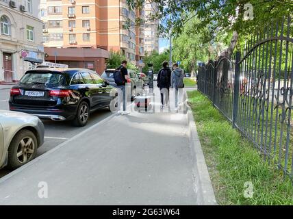 Moscou, Russie, mai 2021: Un petit robot de livraison de nourriture conduit le long de la rue de la ville. Les jeunes marchent au-delà de lui. À côté du robot se trouve Banque D'Images