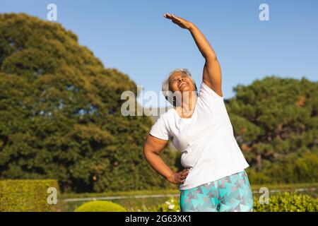 Femme afro-américaine souriante pratiquant le yoga dans un paysage magnifique Banque D'Images
