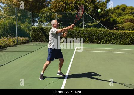 Homme caucasien senior jouant au tennis sur le court tenant une raquette de tennis Banque D'Images