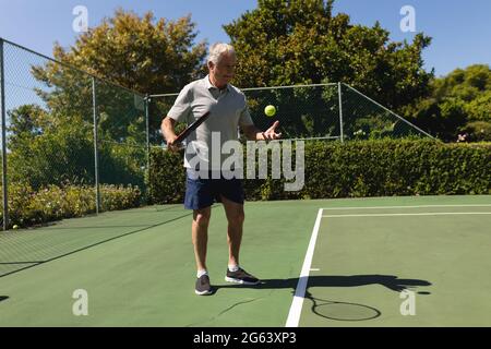 Homme caucasien senior jouant au tennis sur le court tenant une raquette de tennis Banque D'Images