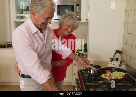 Un couple caucasien de haut niveau cuisant ensemble et souriant dans la cuisine Banque D'Images