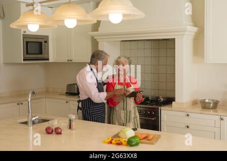 Couple caucasien senior utilisant une tablette ensemble dans la cuisine Banque D'Images