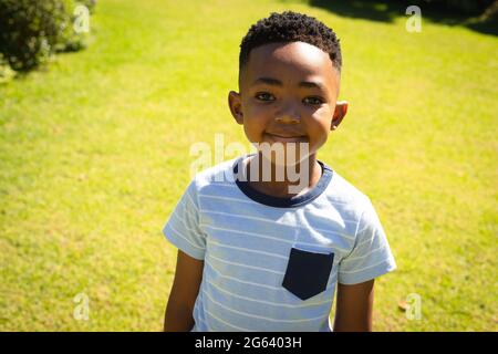 Portrait d'un garçon afro-américain heureux à l'extérieur, souriant dans un jardin ensoleillé Banque D'Images