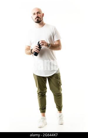 Cool bald barbu jeune homme marchant dans des vêtements décontractés ouvrant réservoir d'eau. Portrait du corps entier isolé sur fond blanc Banque D'Images