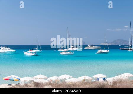 Bateaux de luxe ancrés près d'une plage à Formentera, Mer méditerranée, Espagne. Sur la plage, parasols et sable blanc Banque D'Images