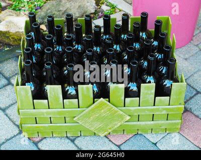 De nombreuses bouteilles de vin vides sont disposées dans une boîte en bois vert sur les dalles Banque D'Images