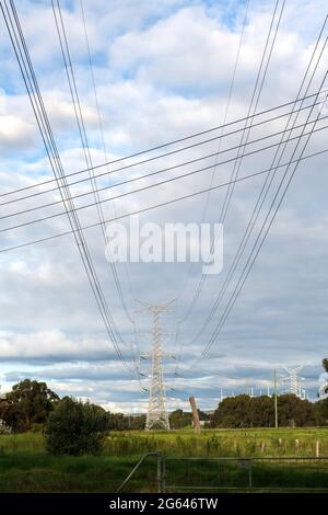 Les lignes électriques haute tension et haute tension se croisent avec les lignes électriques résidentielles locales dans une zone rurale hors-ville. Banque D'Images