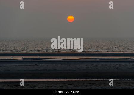 Soleil orange sur la mer du Nord vu de la plage de l'île des Wadden de Terschelling aux pays-Bas Banque D'Images