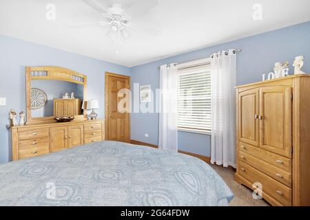 Cette chambre confortable est dotée de murs bleus, d''un mobilier en bois naturel et de moquette. Banque D'Images