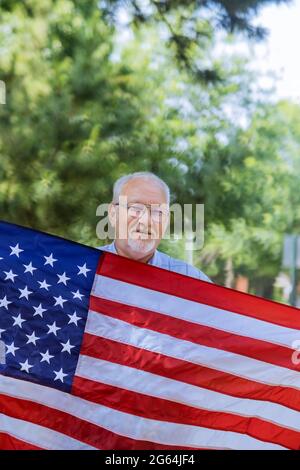 Le jour de l'indépendance dans un patriote senior heureux tient une étoile et affiche un grand drapeau américain Banque D'Images