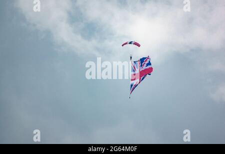 Le membre de l'équipe de l'exposition parachutiste de Red Devil descend avec un énorme drapeau syndical en remorquage Banque D'Images