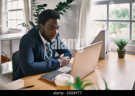 Jeune homme noir travaillant dans un bureau moderne - Focus sur le visage Banque D'Images