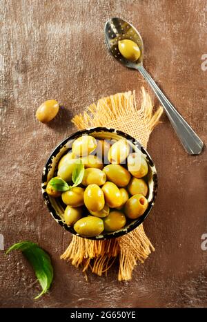 Olives vertes et feuilles de basilic sur fond de bois Banque D'Images