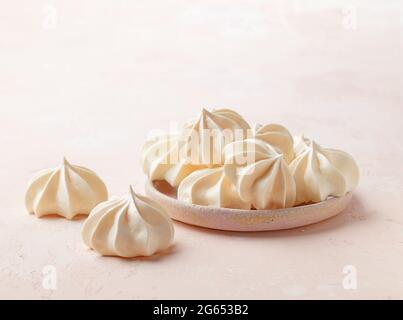 assiette de petits gâteaux de meringue fraîchement cuits sur fond rose Banque D'Images