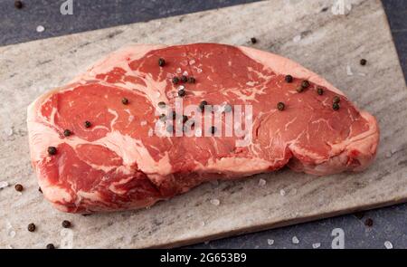 Un steak de New York brut sur une surface d'ardoise foncée Banque D'Images