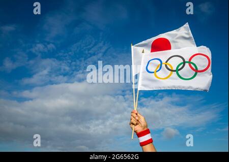 RIO DE JANEIRO - VERS MARS 2016 : drapeau olympique et japonais tenu à la main d'un athlète portant un bracelet rouge et blanc qui flotte ensemble Banque D'Images