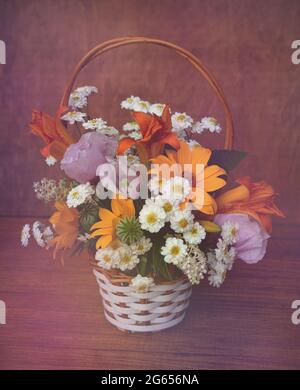 Panier en osier de fleurs d'été sur fond de bois Banque D'Images