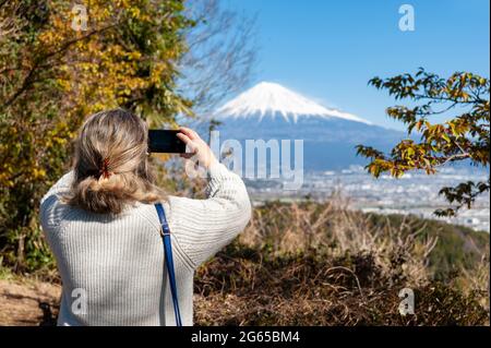 Femme prenant une photo du Mont Fuji, avec une vue aérienne de la ville de Fuji. Photo prise de Noroshiba, Kanbara, Shimizu Ward, Shizuoka Keno. Banque D'Images