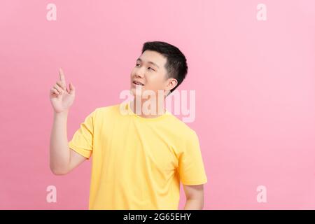 Portrait d'optimiste drôle Guy point vide espace porter t-shirt jaune isolé sur fond rose Banque D'Images