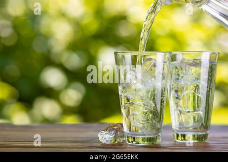 l'eau de la verseuse coule dans le verre avec des glaçons Banque D'Images