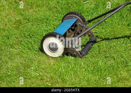 Gros plan pousser la tondeuse à main dans l'herbe de la pelouse dans un jardin hollandais en juillet. Banque D'Images