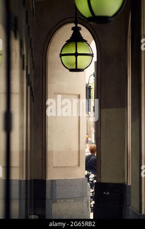 Vue sur le passage couvert à côté de l'arcade de luxe contemporain bâtiment montrant des lignes verticales, vue partielle d'une personne et lumière ornée. Banque D'Images