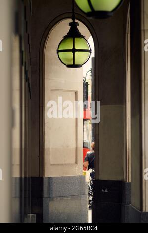 Vue sur le passage couvert à côté de l'arcade contemporaine de luxe bâtiment montrant des lignes verticales, vue partielle d'une personne et le bus rouge de londres et Banque D'Images