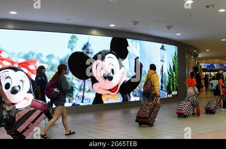 Orlando, États-Unis. 02 juillet 2021. Les voyageurs se promiseront devant un panneau annonçant Walt Disney World à l'aéroport international d'Orlando alors que le week-end des fêtes du 4 juillet commence. Les Américains devraient voyager en nombre record au cours de la fête de l'indépendance. Crédit : SOPA Images Limited/Alamy Live News Banque D'Images