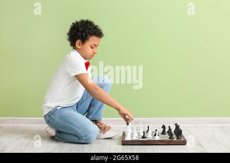 Mignon garçon afro-américain jouant aux échecs à la maison Banque D'Images