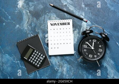 Composition avec calendrier à feuilles de papier, papeterie et réveil sur fond de couleur Banque D'Images