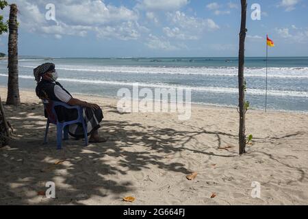 Badung, Bali, Indonésie. 3 juillet 2021. Une police traditionnelle balinaise de Pecalang s'assoit près de la plage pendant qu'il garde la plage des visiteurs. La célèbre plage de Bali Kuta est fermée le premier jour de la mise en œuvre de Java et Bali Emergency Community Activities restriction (PPKM). Le gouvernement central de l'Indonésie imposera le PPPKM Emergeny du 3 au 20 juillet 2021, afin de réduire les dernières ondes massives de Covid-19. Credit: Dicky Bisinglasi/ZUMA Wire/Alay Live News Banque D'Images